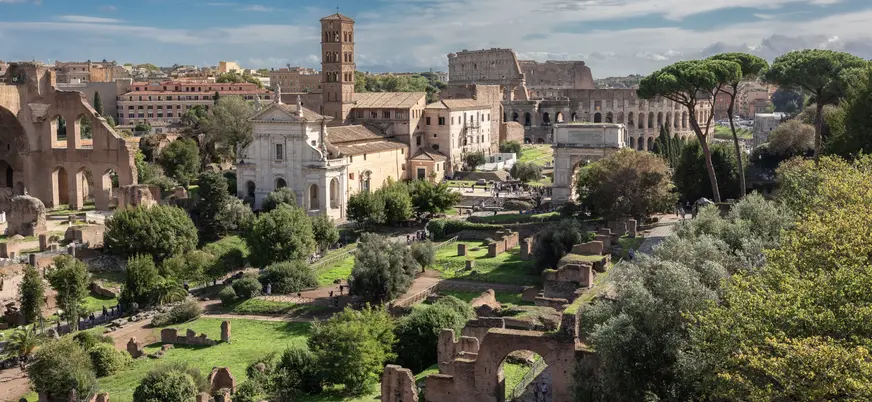 Vista del Foro Romano en Roma con ruinas, vegetación y el Coliseo al fondo