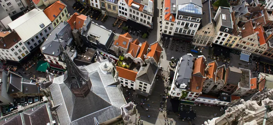 Vista aérea de los tejados del centro histórico de Amberes, Bélgica, con calles, plazas y la aguja de una iglesia gótica.