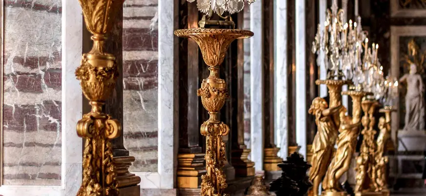Estatuas doradas y lámparas en un largo pasillo del exterior del Palacio de Versalles.