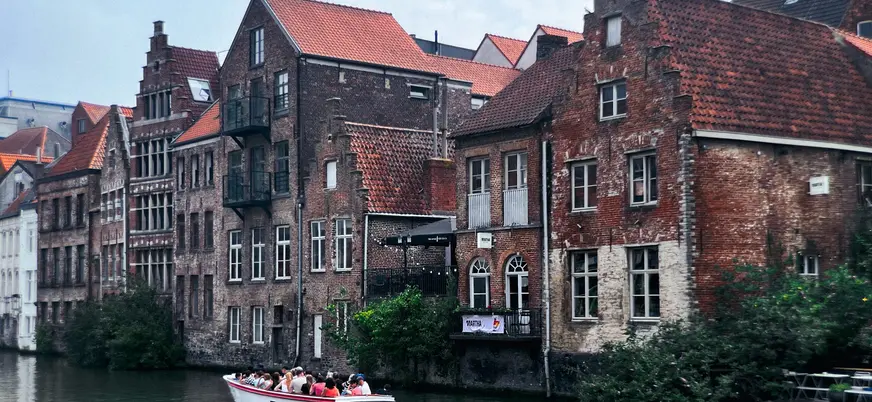 Barco con turistas navegando por los canales junto a casas antiguas de Gante