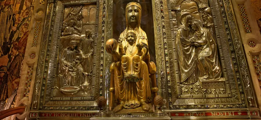 La Moreneta, patrona de Cataluña, estatua de la Virgen de Montserrat en oro, rodeada de relieves metálicos.