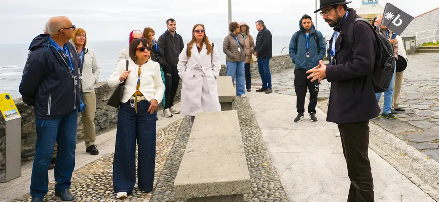 Guía de buendía hablando ante un grupo junto al faro de Luarca, Asturias