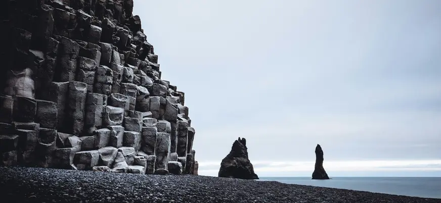 Formaciones de basalto en la playa negra de Reynisfjara, Islandia, frente a los pilares marinos Reynisdrangar.