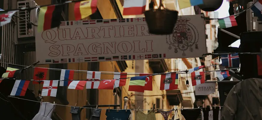 Cartel de entrada al barrio español, rodeado de banderines de países