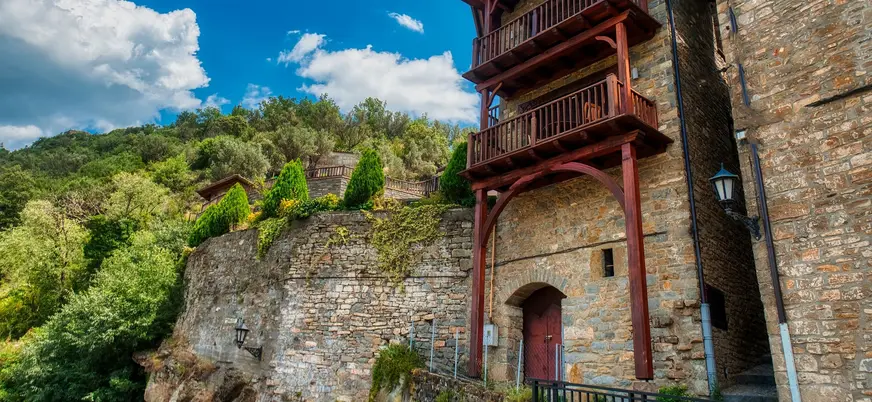 Edificio de piedra tradicional con balcones de madera en un acantilado de Aínsa.