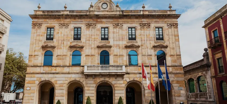 Fachada principal del Ayuntamiento de Gijón, edificio histórico con arcos y balcones en la Plaza Mayor de la ciudad