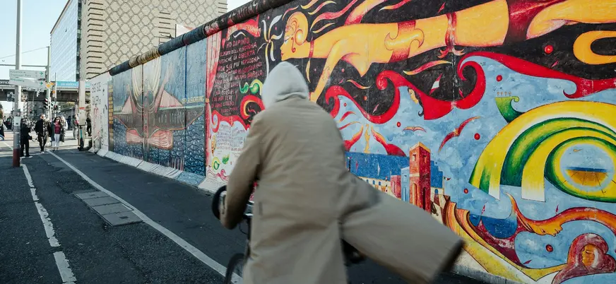 Persona en bicicleta pasando junto a los coloridos murales del Muro de Berlín en la East Side Gallery