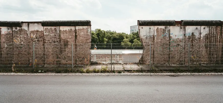 Sección conservada del Muro de Berlín con una apertura y valla metálica en primer plano