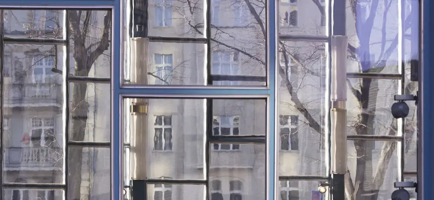 Reflejo distorsionado de un edificio y árboles en las ventanas del Tränenpalast en Berlín