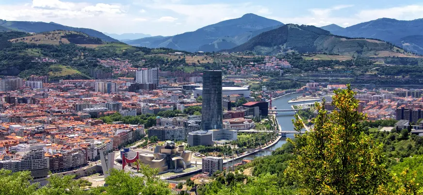 Vista panorámica de Bilbao con el Guggenheim, la torre Iberdrola y montañas al fondo.