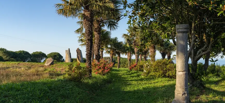 Jardines de Fonte Baxa con palmeras y restos históricos en Luarca, Asturias
