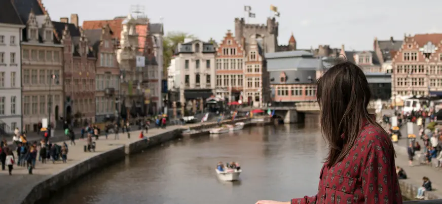 Mujer observando el canal de Gante con el Castillo de los Condes al fondo.