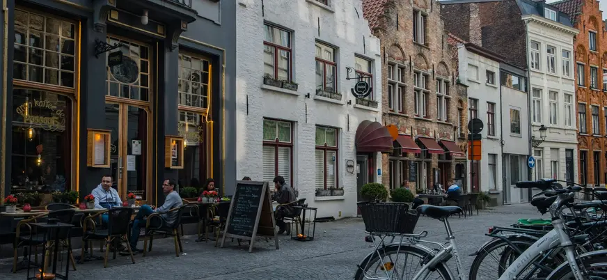 Personas sentadas en la terraza de un café en una calle de Brujas