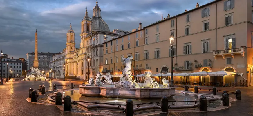 Fuente de Neptuno iluminada en la Piazza Navona de Roma al atardecer.