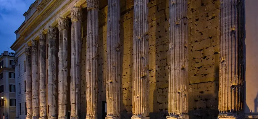 Columnas iluminadas del Templo de Adriano al anochecer en la plaza de Piedra, Roma.