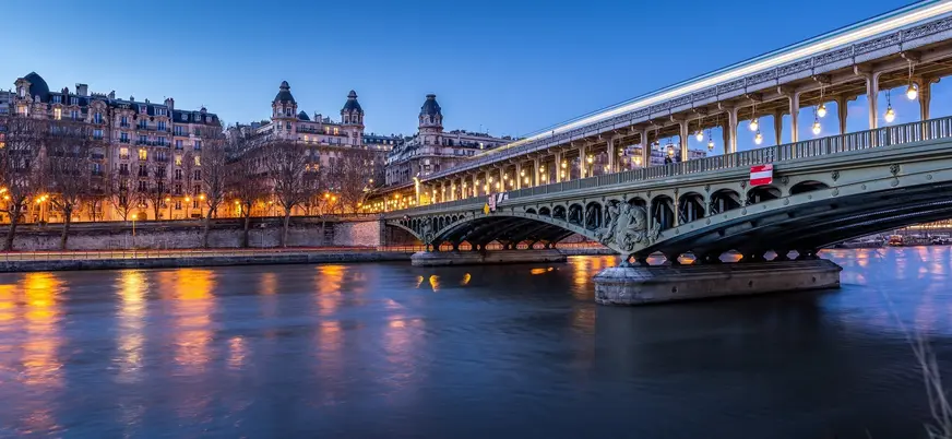 Puente de Bir-Hakeim iluminado sobre el río Sena al atardecer en París.