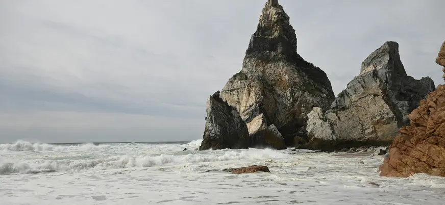 Acantilados y rocas puntiagudas en una playa con fuerte oleaje en Cabo da Roca.