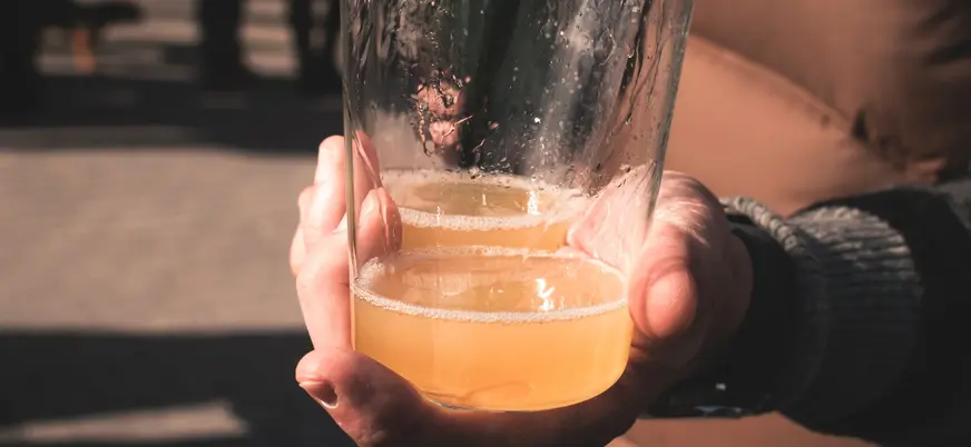 Mano sosteniendo un vaso de sidra natural escanciada en Cangas del Narcea.