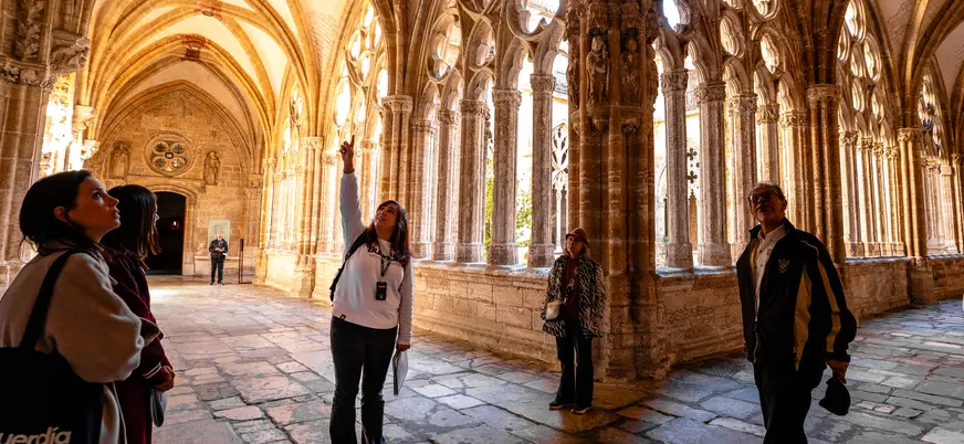 Turistas con guía de buendía observando los arcos góticos del claustro de la Catedral de Oviedo.