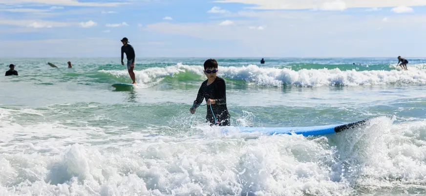 Niño en clase de surf entre olas en la playa de Mundaka, Vizcaya