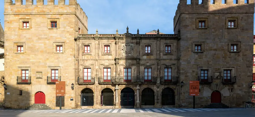 Fachada del histórico Palacio de Revillagigedo en Gijón, construido en piedra con torres y balcones frente a una plaza