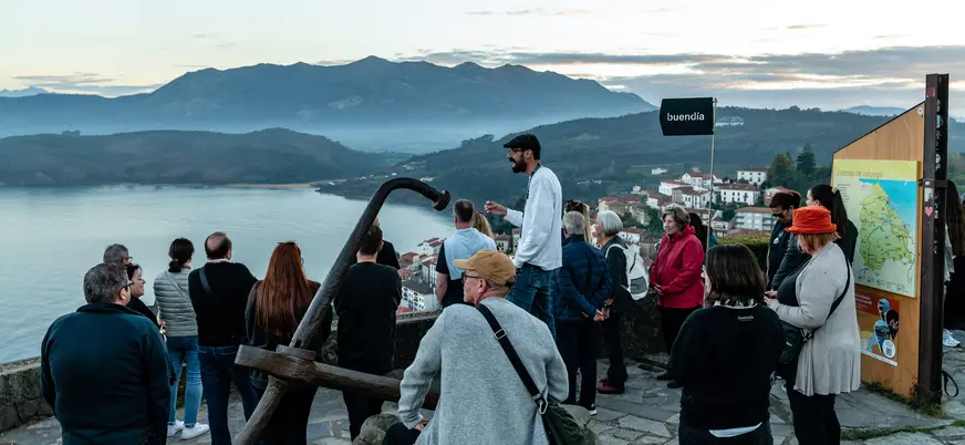 Turistas con guía de buendía en el mirador de San Roque en Lastres con vistas a la costa.