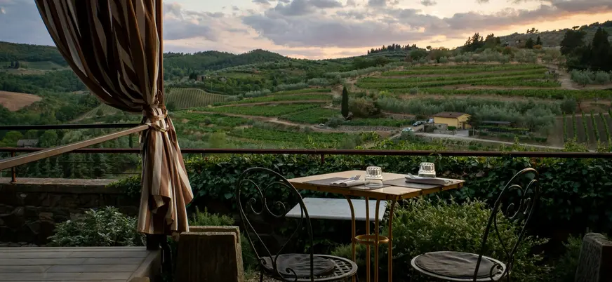 Mesa servida en una terraza con vistas a los viñedos de la Toscana