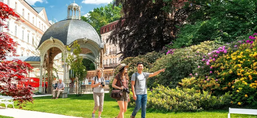 Excursionistas caminando por el parque de la Columnata de la Fuente en Karlovy Vary
