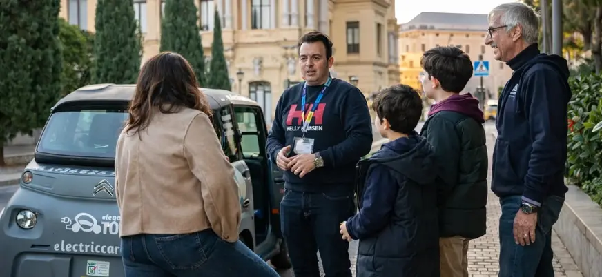 Guía explica tour a las cuevas del tesoro en coche eléctrico a una familia en Málaga, España.