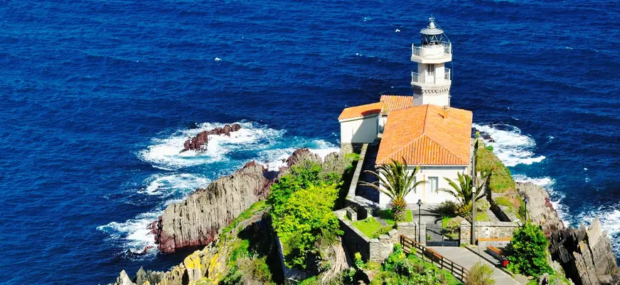 Faro de Cudillero sobre el acantilado rodeado por el mar Cantábrico