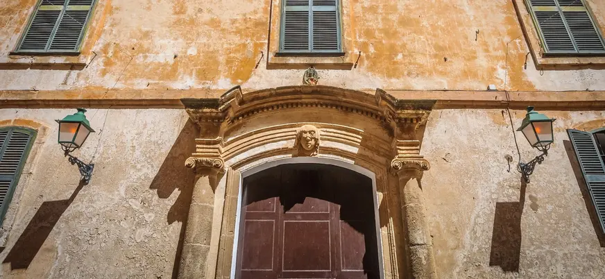 Fachada de palacio señorial en Ciutadella con portal barroco y faroles de forja
