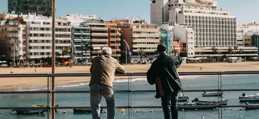 Personas mirando el mar y barcas en la Playa de Las Canteras, Las Palmas.