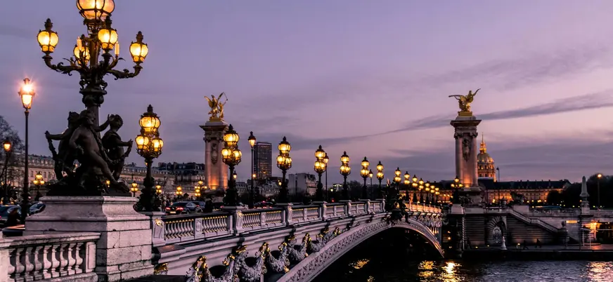 Puente Alejandro III iluminado al anochecer con el río Sena de fondo en París