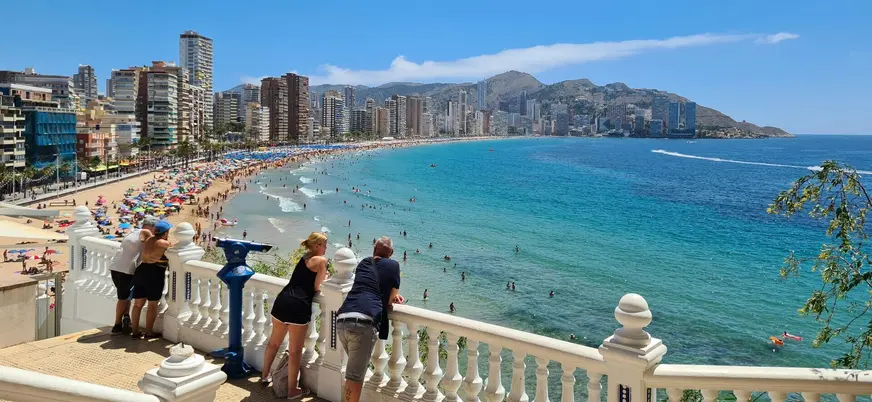 Personas observando la playa de Levante desde el mirador del paseo en Benidorm