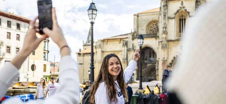 La guía señala la Catedral de Oviedo mientras le toman una foto.