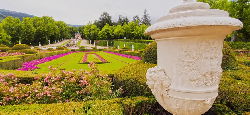 Urna de mármol en primer plano y parterres rosados en el Palacio de la Granja