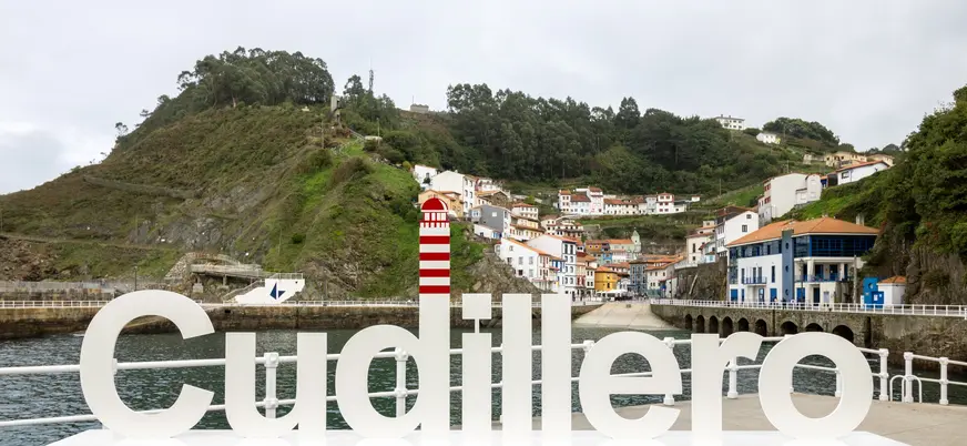 Letrero gigante de Cudillero en el puerto con el pueblo de fondo, Asturias