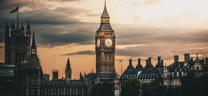 Torre del Big Ben y Palacio de Westminster bajo un cielo nublado al atardecer.