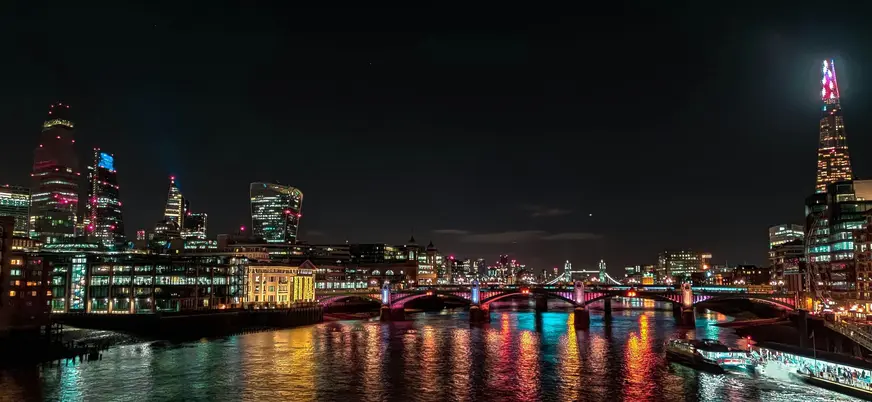 Puente de Southwark y rascacielos iluminados sobre el río Támesis de noche.