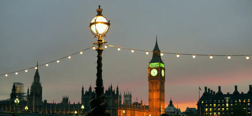 Big Ben iluminado tras farolas y guirnaldas de luces junto al Támesis.