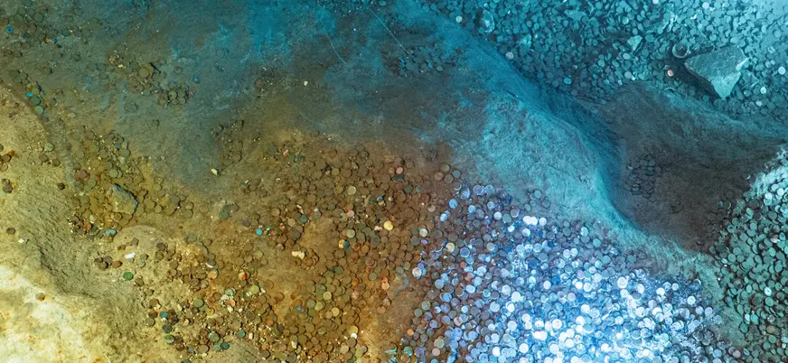 Monedas acumuladas en el fondo de la Cueva del Tesoro en Rincón de la Victoria.