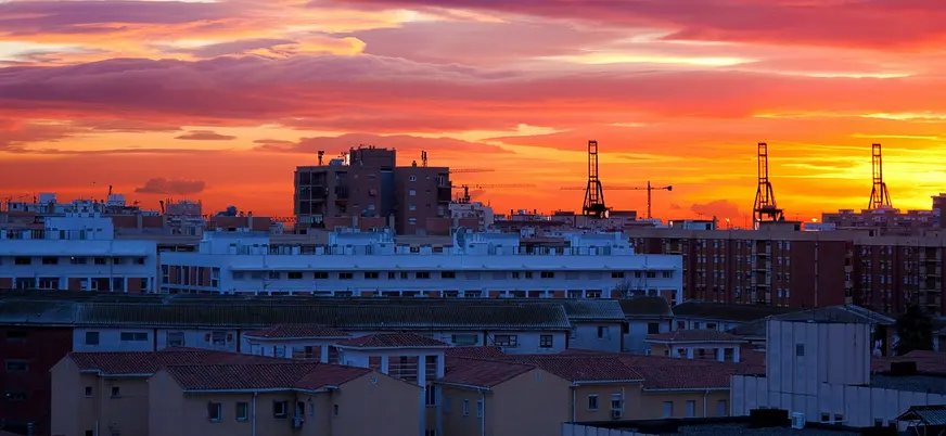 Atardecer sobre edificios y grúas del puerto de Málaga, España.