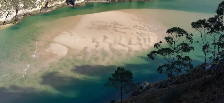 Banco de arena y aguas turquesas en la costa de Pechón, Cantabria.