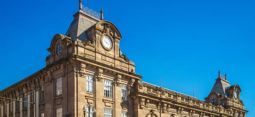 Fachada monumental de la estación São Bento en Oporto bajo cielo azul.