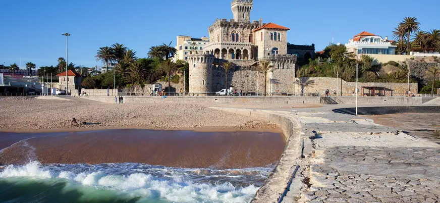 Playa de Tamariz con el castillo de Estoril junto al mar en un día despejado.