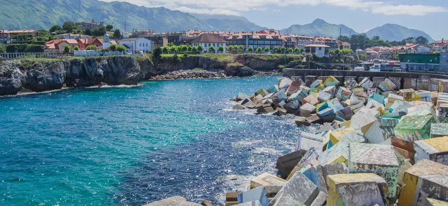 Cubos de la Memoria coloridos en el puerto de Llanes con montañas al fondo