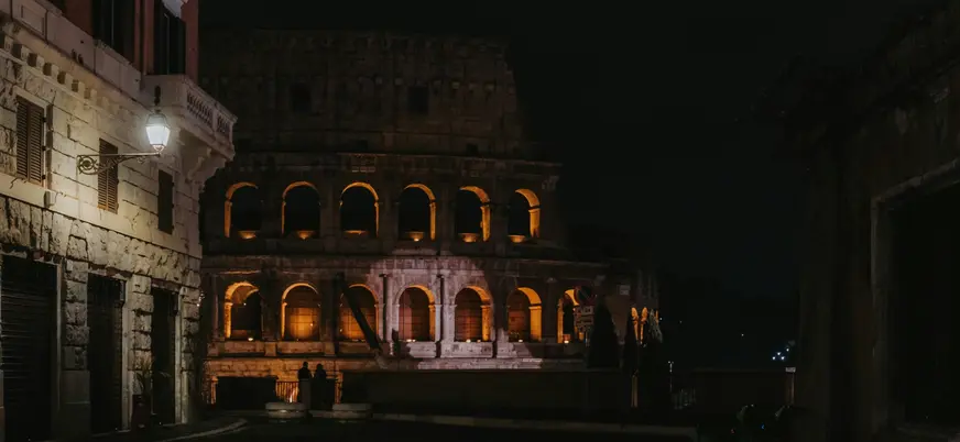 Coliseo de Roma iluminado de noche visto desde una calle cercana y tranquila