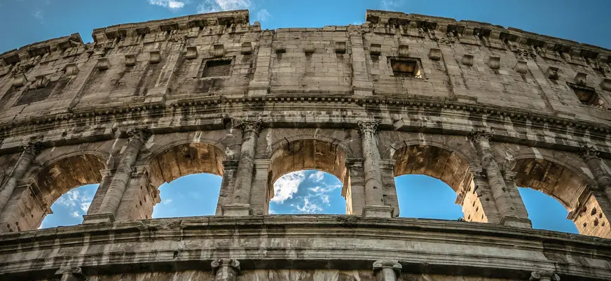 Coliseo de Roma en Italia visto desde abajo con arcos iluminados por el cielo azul