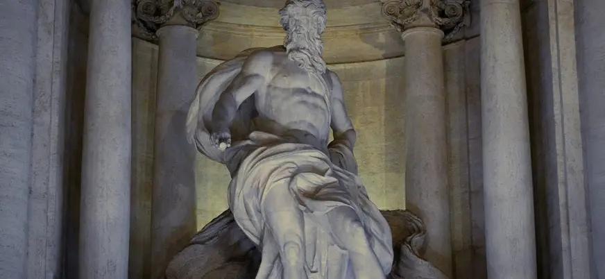 Escultura iluminada de la Fontana di Trevi en Roma con columnas clásicas detrás