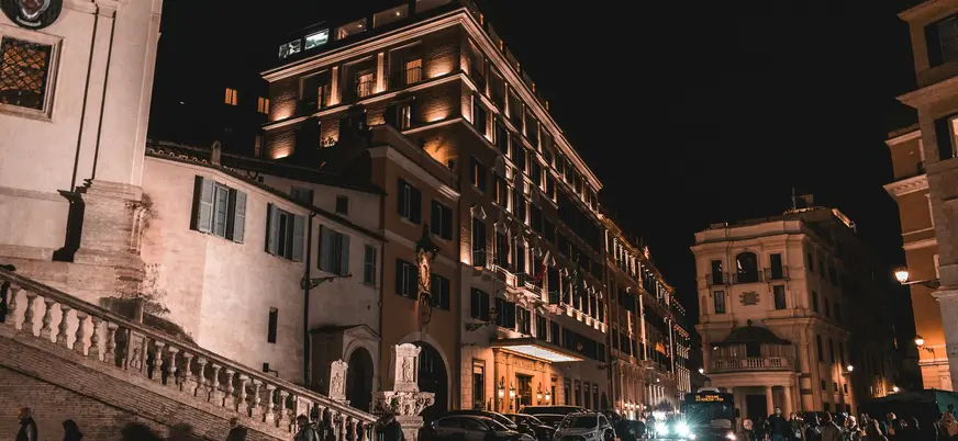 Calle iluminada de Roma de noche con edificios históricos y gente paseando